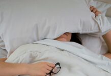 뱃살 타파의 신비, 수면의 역할 person lying on bed while covering face with pillow and holding eyeglasses