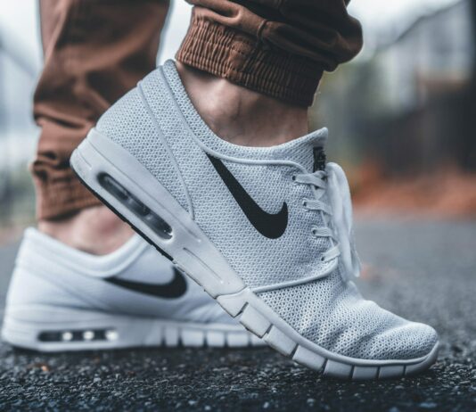 여름철 신발 선택과 발 건강 person wearing white Nike running shoes standing on black concrete path