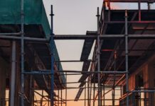 1기 신도시 ‘재건축’ 2027년 첫 삽…도시정비 가이드라인 마련 scaffolding surrounding a building with the sun setting in the background