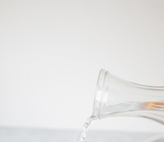 여름철 운동 중 더위를 피하는 방법 A pitcher pouring water into a glass filled with orange slices