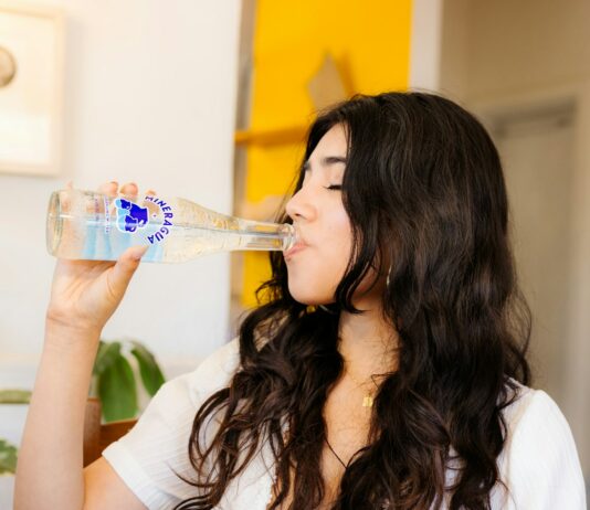 운동 성과를 극대화하는 식사법: 최적의 영양 섭취 타이밍 a woman drinking water from a plastic bottle