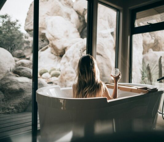 차가운 날씨 속 힐링을 위한 온천 여행 woman in white bathtub holding clear drinking glass