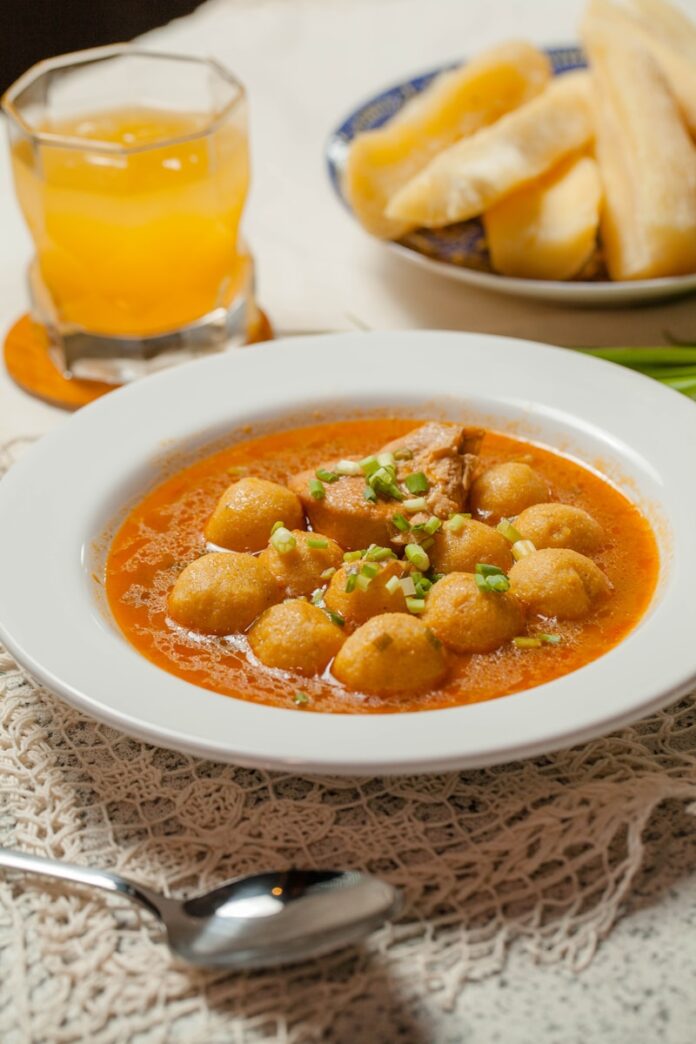 A bowl of soup on a table with a glass of orange juice
