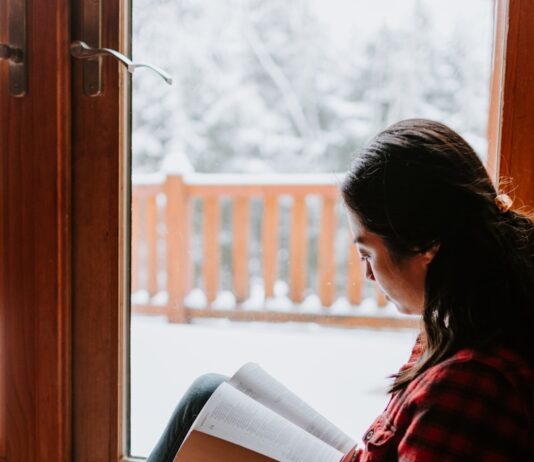 스트레스를 줄이는 겨울철 독서의 효과 woman in red and black striped long sleeve shirt and blue denim jeans sitting on brown