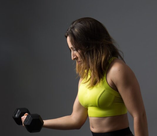 고혈압이 심장 건강에 미치는 영향: 예방과 치료 woman wearing pink sports bra holding dumbbells