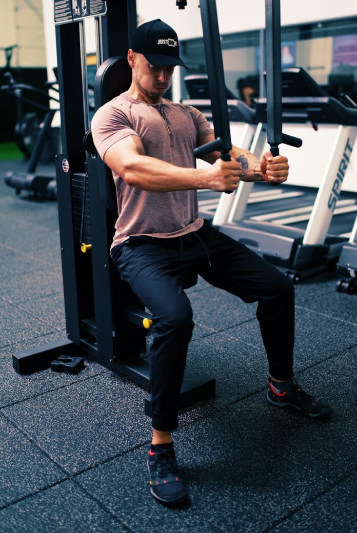 man in gray t-shirt and black pants sitting on black and white metal bar