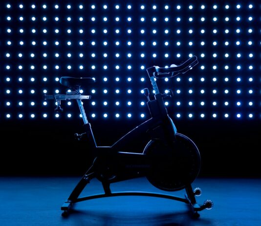 40대 이후 운동 방법: 관절 보호와 근육 유지 전략 a stationary exercise bike in front of a blue background