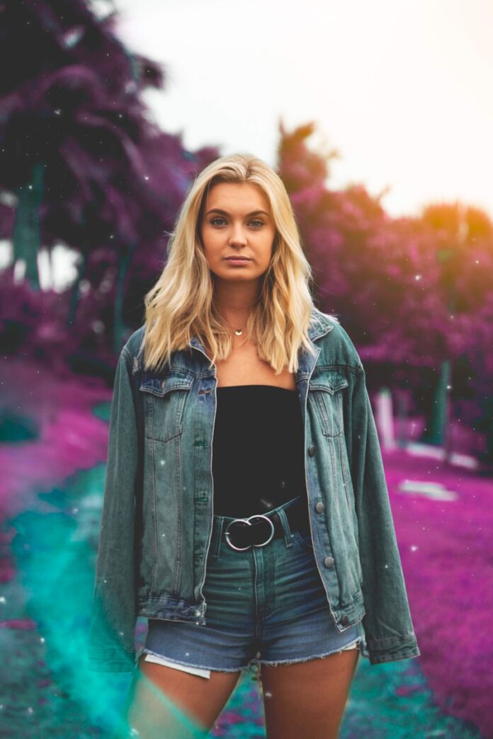 woman standing wearing denim jacket and short shorts