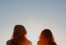 갱년기 증상 완화와 호르몬 건강, 현명하게 관리하는 방법 two woman sitting on beach sand while facing sunlight