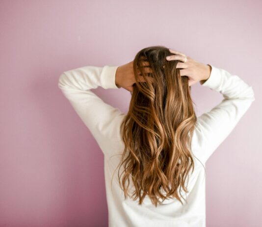 여름철 헤어 건강을 지키는 5가지 팁 woman in white long-sleeved shirt standing in front of pink wall