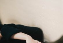 만성피로, 단순한 피로가 아닌 ‘경고 신호’…원인과 극복 방법은? woman in black long sleeve shirt covering her face