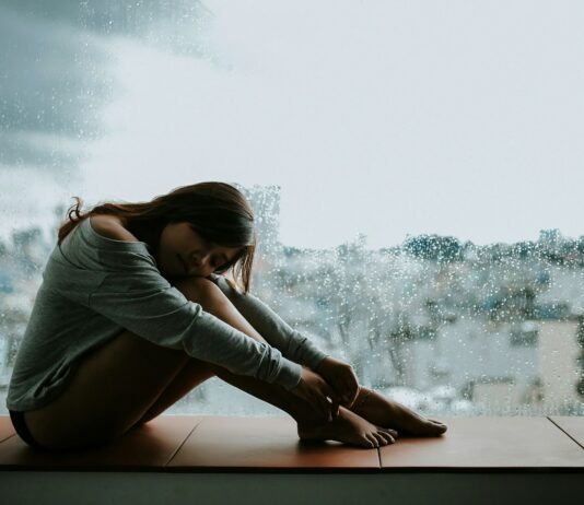 “10억 명이 정신건강 문제”… WHO, 서비스 확충 시급성 강조 woman in gray long sleeve shirt sitting on window