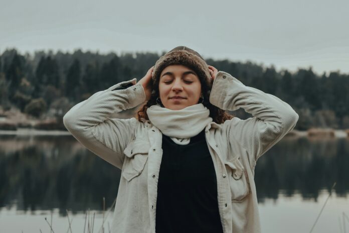 woman in beige coat covering her eyes with her hand