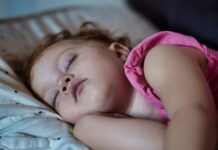 수면의 질이 건강을 결정한다…충분한 잠이 필요한 이유 a little girl sleeping on a bed with her eyes closed