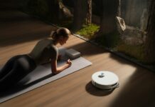 만성피로, 알아두면 건강 지키는 첫걸음 Woman planks on mat near robot vacuum cleaner.