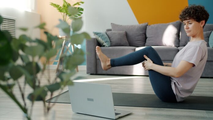 Woman doing yoga in front of a laptop