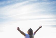 웰니스 문화, ‘나’를 돌보는 새로운 라이프스타일로 떠오르다 woman in white shirt and black pants standing on rocky mountain during daytime