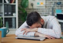만성피로, 단순한 휴식으로 해결 안된다…새로운 접근법 필요 a man sitting at a desk with his head in his hands