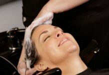 “두피 관리부터 ‘저자극 펩타이드’까지, 건강한 헤어 트렌드 총정리” A woman enjoys a hair wash at a salon.