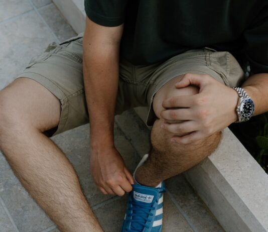 “움직여야 덜 아프다”… 무릎 관절염, 통증을 줄이는 세 가지 운동법 A man sitting on a ledge tying his shoes