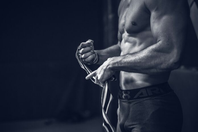 a shirtless man holding a pair of gloves