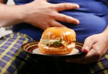 “밥만 먹으면 바로 배가 불러요”… 위장이 보내는 ‘숨은 경고’ a person holding a plate with a sandwich on it