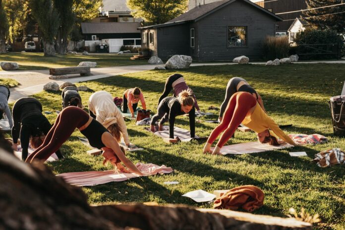 Photo by Marea Wellness a group of people doing yoga in the grass