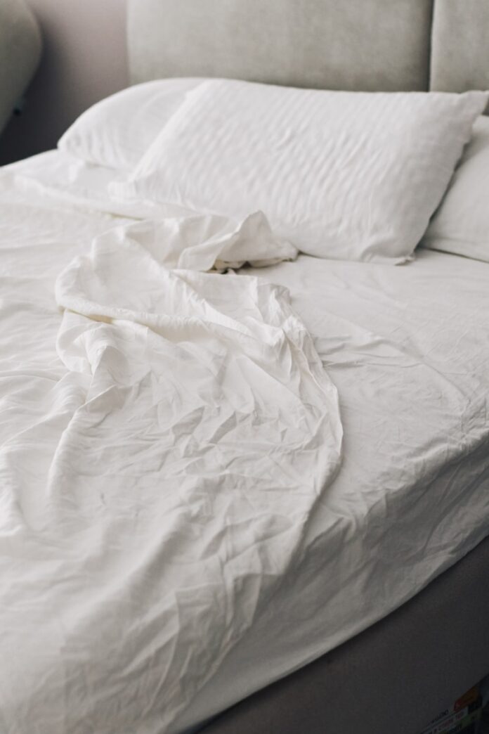 Photo by Dina Makhmutova A rumpled white bed with pillows