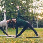 일과 삶의 경계가 흐려지는 시대의 회복 루틴: 직장인 스트레스와 건강 Two women practicing yoga in a park.