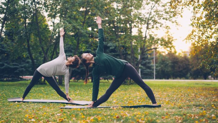 Photo by Vitaly Gariev Two women practicing yoga in a park.