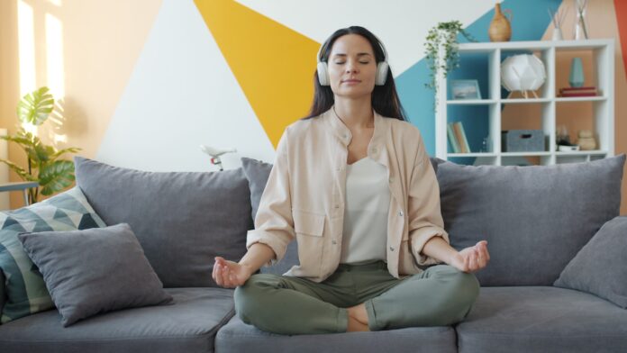 Woman meditating on couch with headphones on