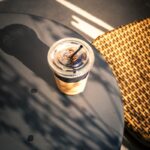 “마음을 지키는 작은 습관, 일상 속 스트레스 관리법 주목” Iced coffee on a table with dappled sunlight