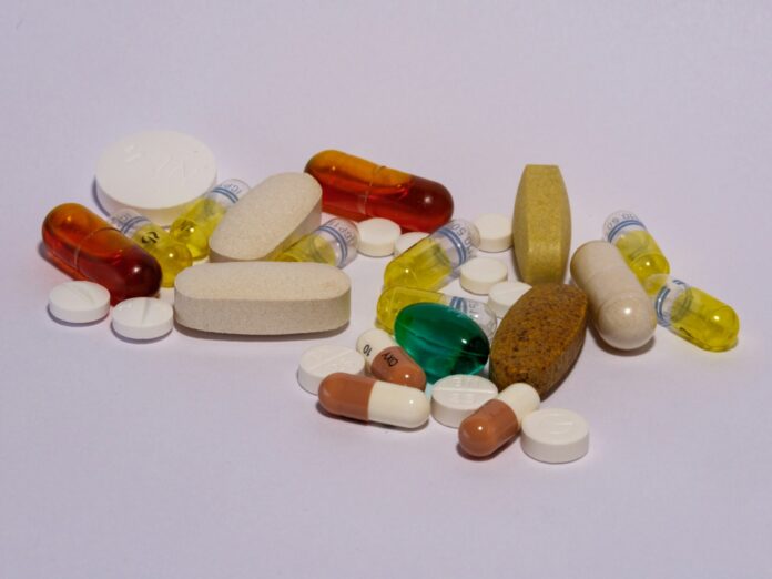 Photo by Haberdoedas A pile of pills sitting on top of a white table