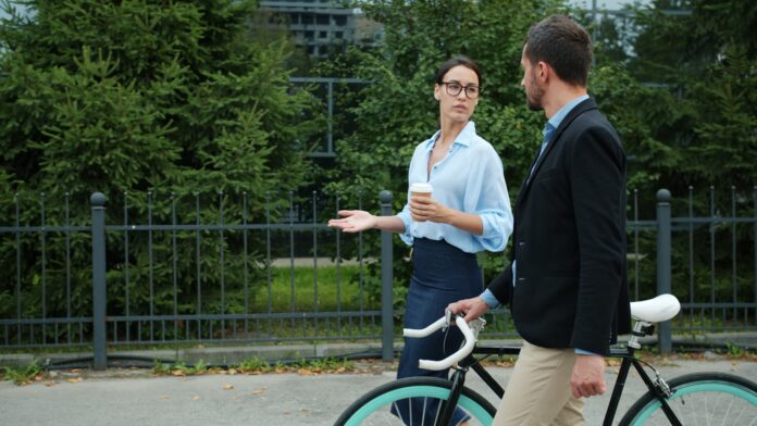 Two colleagues walking with a bicycle outdoors