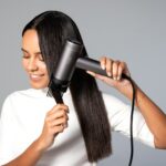 집에서도 건강한 두피와 머릿결…최근 떠오르는 ‘마이크로 관리’ 트렌드 a woman blow drying her hair with a hair dryer