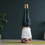 발란스 요가: 나무처럼 곧고 단단하게, 집중력을 높이는 균형 잡기 Woman performing a headstand yoga pose indoors.