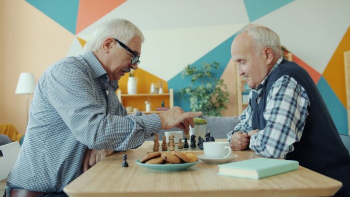 Photo by Vitaly Gariev Two elderly men playing chess at a table.