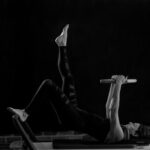 크롭티 핏의 완성, 11자 복근 : 표면이 아닌 ‘심부’를 설계하라 woman in black pants and black boots lying on black wooden bench