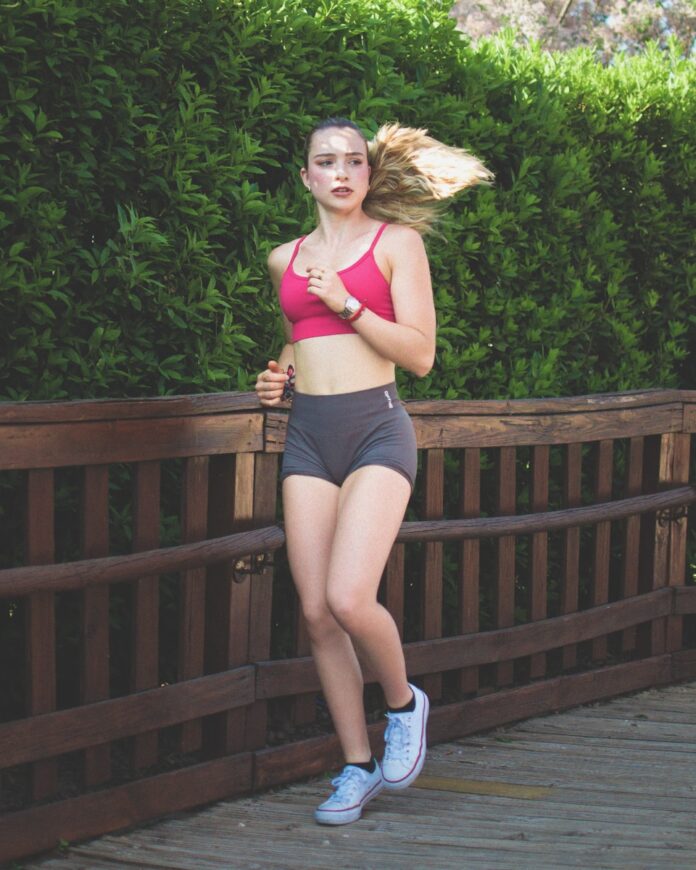 Photo by Gabriel Martin Young woman running on a wooden path outdoors path outdoors.