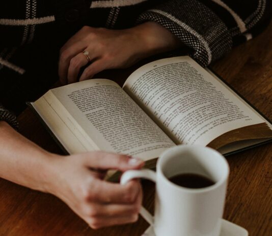 건강한 수면 습관, 꾸준한 실천이 핵심…작은 변화로 큰 효과 A person sitting on the floor with a book and a cup of coffee