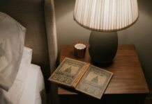 바쁜 일상 속, ‘수면 루틴’이 건강 트렌드로…실생활 적용 팁은? Open book on bedside table with lamp