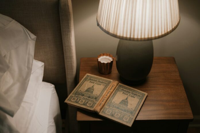 Photo by Clay Banks Open book on bedside table with lamp
