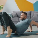 슬림 레그 가이드: 부기 없는 매끈한 다리 라인을 위한 하체 순환 Man doing yoga on a mat in a living room.