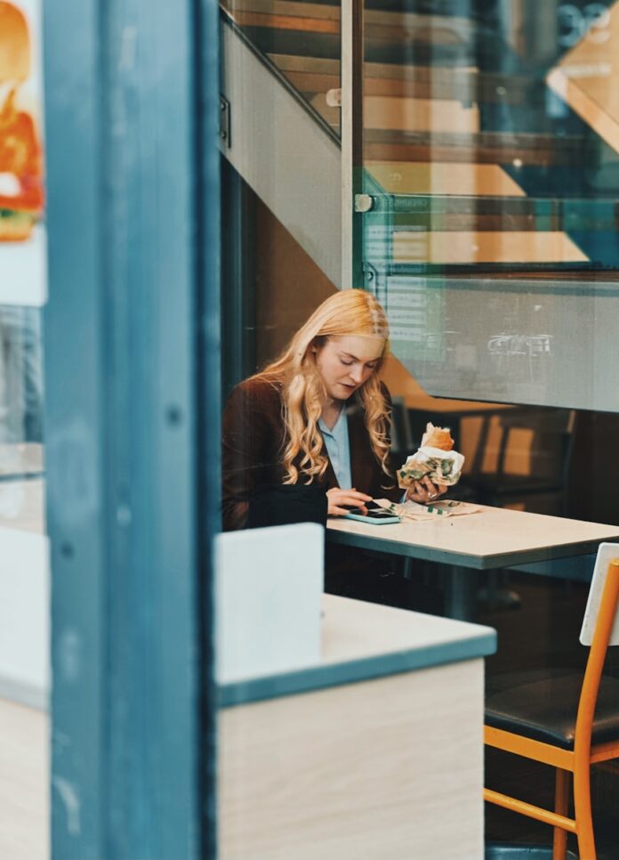 Woman eating a sandwich at a cafe table.