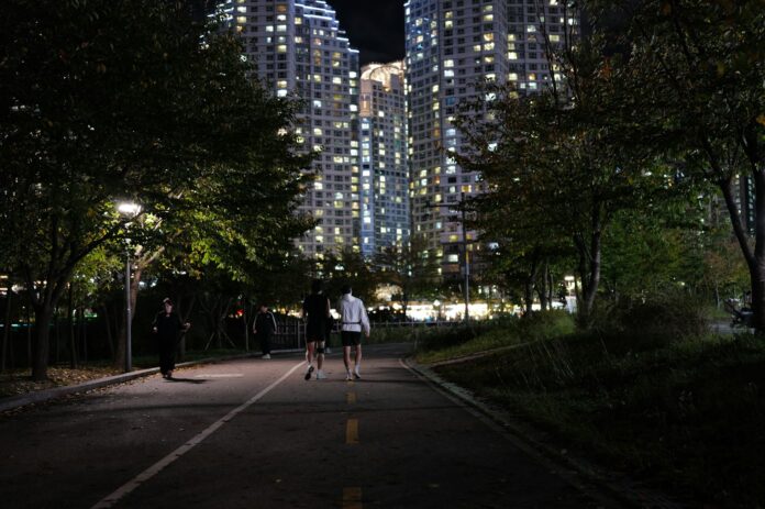 Photo by Jisu Han People jogging on a path at night near apartments.