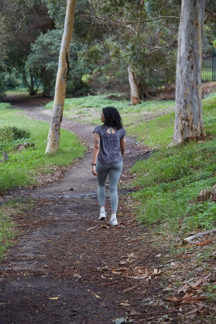 Photo by Sweet Life a woman is walking down a path in the woods