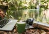 스마트폰 과몰입 시대, 일상에서 실천하는 ‘디지털 디톡스’ 건강 루틴 Laptop, camera, and mug by a forest stream