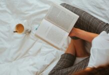 ‘자기 전 스마트폰 멀리하기’…현대인의 숙면, 작은 실천에서 시작된다 person in black and white striped long sleeve shirt reading book