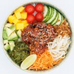 “맛있게, 건강하게! 요즘 뜨는 식단 트렌드와 실생활 실천법” A colorful poke bowl with fresh ingredients and chicken.