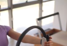 집에서도 쉽게 시작하는 필라테스, 일상의 새 활력소로 주목 a woman sitting on the floor holding a steering wheel